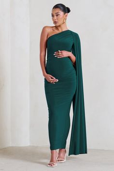 For a stunning maternity look that will always be remembered. take a look at our gracious Amaryllis gown. This green bodycon dress is made from a premium stretch jersey that's double-lined for comfort and support. Finished with a sweeping cape sleeve and a split skirt. this asymmetric maxi dress deserves a place in your maternity wardrobe.Features- Premium stretch jersey- Asymmetric neckline- Single cape sleeve- Invisible zip closure- Bodycon fit- Bump ruching- Split hemline- Maxi lengthSizing & Elegant Pregnancy Outfits, Pregnant Bridesmaid Dress, Vestidos Para Baby Shower, Green Maternity Dresses, Maternity Picture Outfits, Elegant Fashion Outfits, Dress With Cape, Green Bodycon Dress, Maternity Wardrobe