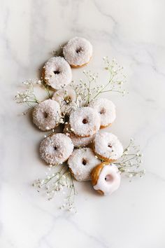 donuts with sprinkles and flowers on a marble surface