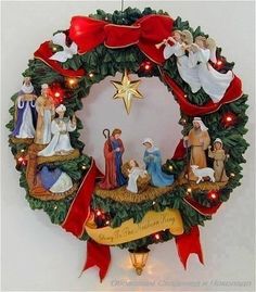 a christmas wreath hanging on the wall with nativity figures and lights around it,