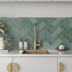 a kitchen with green tiles on the backsplash and brass faucet in the sink