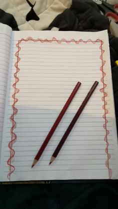 an open notebook with two pencils on it