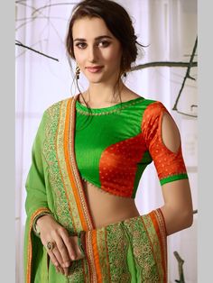 a woman in a green and orange sari with her hands on her hips, posing for the camera