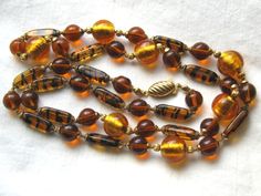 This is a gorgeous 32 inches long vintage tiger stripe beaded necklace. It is hand strung and painstakingly knotted between the gold tone end caps of each bead. This necklace was made in the 1960s or 1970s. The scalloped gold tone clasp is fish hook style.    There are four different kinds of beads in the strand: There are lozenge shaped honey color beads with black stripes (my favorites). They remind me of tiger stripes. There are also large 12mm round beads with shimmering, mottled gold tone i Celluloid Jewelry, Vintage Tiger, Honey Color, Vintage Jewelry Art, Tiger Stripes, Amber Jewelry, Art Deco Jewelry, Etsy Jewelry, Vintage Costume Jewelry