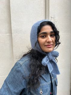 a woman with long hair wearing a denim jacket and a knitted scarf around her head