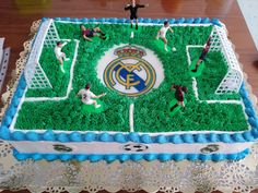 a cake that is shaped like a soccer field with people standing on the grass in front of it