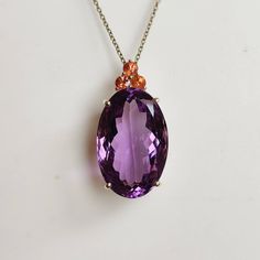 ITEM DESCRIPTION: >> The pendant is made from Solid 14K Yellow Gold. Gemstone used is absolutely natural and ethically sourced.  >> Natural Purple Amethyst in Emerald cut and Pear shape with prong setting is studded on it with utmost precision.. >> This is a minimalist design and is absolutely hassle-free and everyday jewelry.  Gem: Purple Amethyst Gem size & shape: 14x22 mm & Oval Gem weight: 19.75 carats Gem: Orange Sapphire Gem size & shape: 3 mm & Round Gem Weight: 0.40 carats Gem gross weig Orange Sapphire Necklace, Gold Necklace Pendant, Sapphire Gem, Handmade Jewelry Box, Yellow Gold Necklace, Amethyst Gem, Orange Sapphire, Sapphire Pendant, February Birthstone