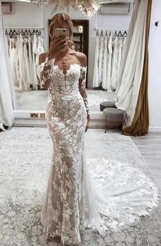 a woman taking a selfie in front of a mirror wearing a white wedding dress