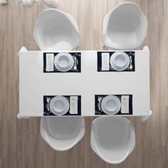 an overhead view of a white table with plates and cups on it in the center