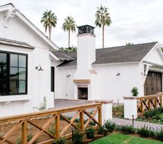 a white house with palm trees in the back ground and a wooden fence around it