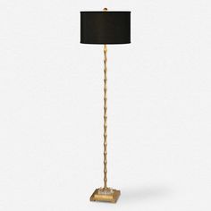 a floor lamp with a black shade on the top and gold trimming around the base