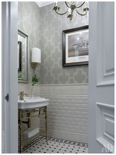 a white sink sitting under a mirror in a bathroom next to a chandelier