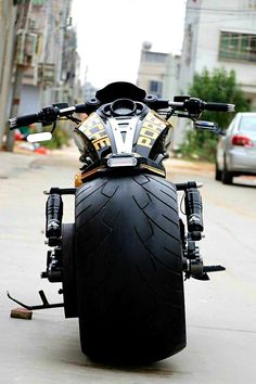 a motorcycle parked on the side of a road next to a street with cars and buildings in the background