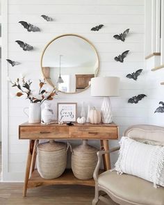 a wooden table topped with two baskets filled with halloween decorations and bats on the wall