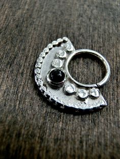 The Sacred Septum is a beautiful septum with a half-circle shape & intricate design with a Black Onyx in the centre. It is made from solid Sterling Silver. Size Guide: ▸ Inner diameter: 8 mm ▸ Total height: 17 mm ▸ Wire: 1,2 mm / 16 gauge DIAMETER The inside diameter of this piece is based on the inner most ring ONLY. Material: 925 Sterling Silver & 3 mm Black Onyx Choose from high-polish or oxidised silver. The oxidised Sterling Silver has a more dark antique look to make the details po Bohemian Black Jewelry With Internally Threaded Details, Pierced Sterling Silver Belly Rings, Silver Sterling Belly Rings, Elegant Handmade Silver Nose Rings, Elegant Silver Septum Ring, Silver Metal Septum Ring As Gift, Gift Silver Metal Septum Ring, Nickel-free Silver Metal Septum Ring, Elegant Sterling Silver Septum Ring