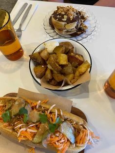 a hot dog on a bun with toppings next to some beer and other food