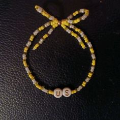 a yellow beaded bracelet with two white beads and the word u s on it