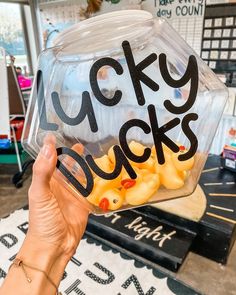 a person holding up a plastic ducky bucket with rubber ducks in it that says lucky ducks