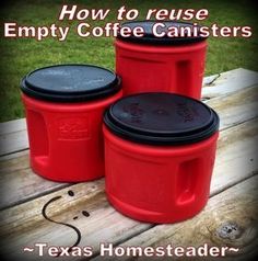 three red and black plastic containers sitting on top of a wooden table next to grass