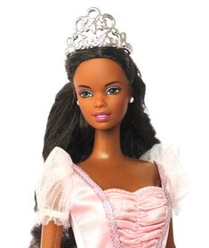 a barbie doll wearing a pink dress and tiara with long black hair in front of a white background