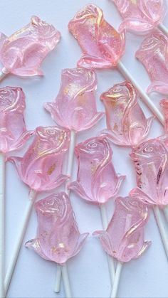 pink lollipops with gold flecks on them are sitting on a white surface