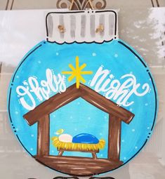 a hand painted glass ornament with a nativity scene on it's side