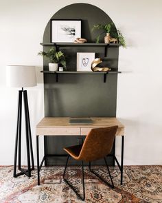 a desk with a lamp and some pictures on the wall above it, along with a chair