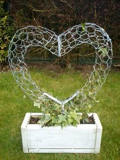 a heart shaped wire sculpture sitting on top of a white planter