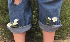 a pair of jeans with flowers painted on them and holes in the bottom half of their legs