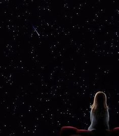 a woman sitting on a bench looking up at the stars