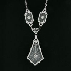 "This is a magnificent antique pendant necklace that was crafted during the art deco period in solid 14k white gold. It features three camphor glass panels with the largest dangling at the center, and each is set with a fine old single cut diamond that adds a lovely touch of sparkle to this piece. The camphor glass displays magnificent etching designs and is elegantly bezel set and framed with etched patterns throughout and further adorned with lovely floral filigree work. The largest camphor gl Luxury Art Deco Necklace With Polished Finish, Victorian White Gold Pendant Necklace, Victorian White Gold Necklaces For Evening, Victorian White Gold Necklace For Evening, Victorian Style White Gold Necklace For Evening, Art Deco Platinum Jewelry For Evening, Antique Diamond Cut Pendant Necklace, Vintage Platinum Pendant Necklace, Art Deco White Gold Platinum Necklace