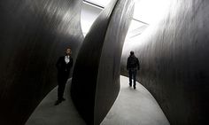 two men are standing in the middle of a room with curved metal structures on either side