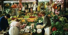 people are shopping at an outdoor market with lots of fruits and vegetables on display in front of them