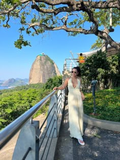 a woman in a long dress standing on a bridge