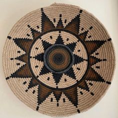 a brown and black basket hanging on the wall in front of a white wall with a circular design