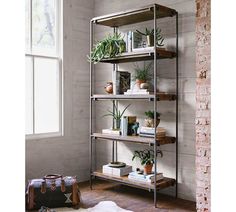 a metal shelf with plants and books on it next to a window in a room