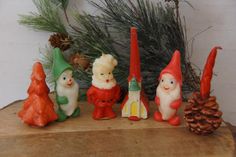 a group of gnome figurines sitting on top of a wooden table next to pine cones