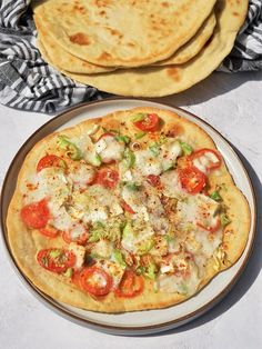 two pizzas sitting on top of a plate next to some pita bread slices