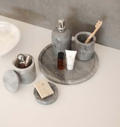 a bathroom sink with soap, toothbrushes and other items on it's tray