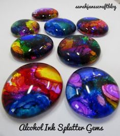 six colorful rocks sitting on top of a white table with the words alcohol ink splatter gems