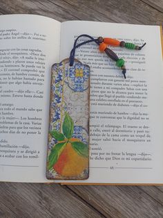 an open book with a tasseled orange and green leaf on it's cover