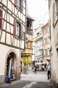 people are walking down the street in an old european town with half - timbered buildings