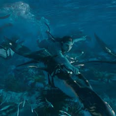 a woman riding on the back of a shark in an ocean with lots of fish