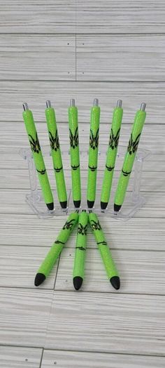 six green and black pens sitting on top of each other