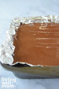 a pan filled with chocolate cake sitting on top of a white countertop covered in aluminum foil