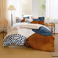 a bed with blue, brown and white comforter in a room next to a window