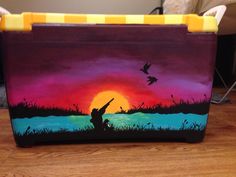 a painted lunch box with a sunset scene on it