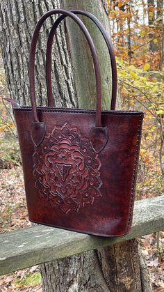 "Fine Hand-Tooled Leather Tote \"MEDALLION\" by ALLE made with full-grain hide, deeply embossed Medallion design in the middle of the bag both sides, beautiful hand-stitched adorning the sides and top of the bag. With a spacious interior and thoughtfully placed pockets, this tote is perfect for everyday life! Perfect as a gift for Mom, Grandma, Girlfriend Made from Full-grain leather, each bag varies in shading due to the thickness which is determined by the age of the animal and the natural cre Brown Embossed Tote Shoulder Bag, Vintage Brown Hand Tooled Bag For Everyday Use, Leather Shoulder Bag Engraved For Everyday Use, Engraved Leather Shoulder Bag For Everyday, Everyday Leather Shoulder Bag Engraved, Brown Embossed Satchel Shoulder Bag, Brown Embossed Satchel Bag, Brown Hand Tooled Tote Shoulder Bag, Brown Hand Tooled Shoulder Bag For Everyday Use