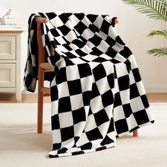 a black and white checkered blanket sitting on top of a chair next to a potted plant