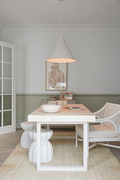 a white dining table with two chairs and a bowl on top of it in front of an open door