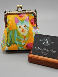 a small purse with a business card holder next to it on a gray background and a wooden stand